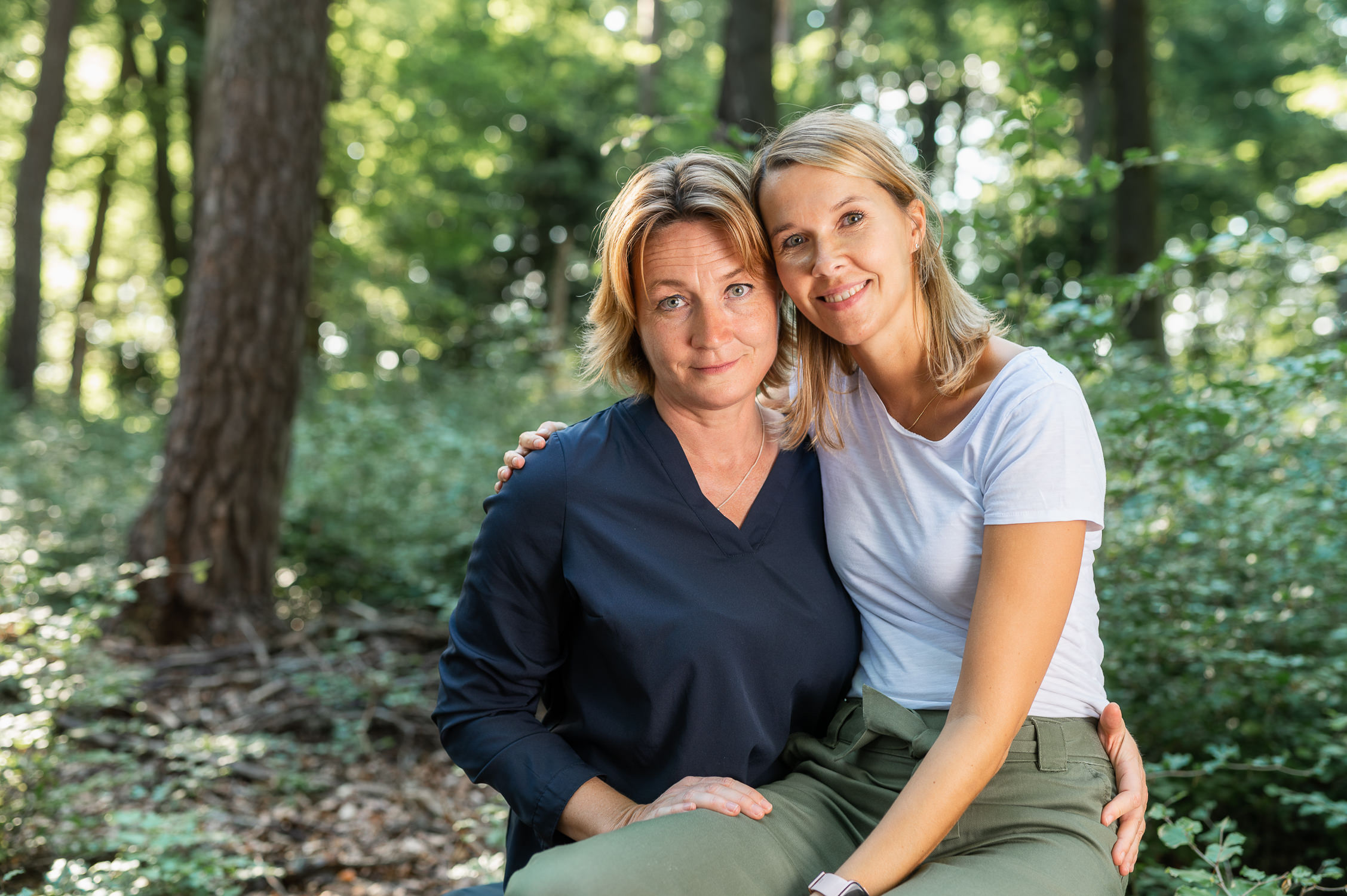 Schwestern sitzen im Wald auf Baumstumpf
